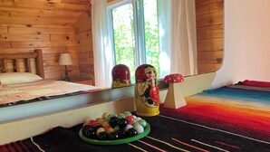 Une pièce de cabane en bois comprenant un lit, une petite table avec un bol rempli de billes colorées et un objet décoratif ressemblant à un champignon.