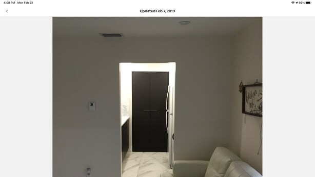 Un salon moderne avec un canapé, une porte donnant sur une autre pièce et un cadre photo fixé au mur.