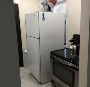 A compact kitchen with a refrigerator, oven, and a microwave.