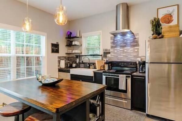 A modern kitchen with a wooden island, stainless steel appliances, and pendant lighting.