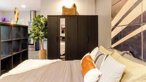 Una camera da letto con un letto, un armadio, una pianta e una parete decorata con un motivo geometrico.