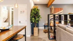 Un soggiorno moderno con un divano, un tavolino e una libreria. Nell'angolo c'è una pianta e una porta con il cartello 'No Smoking'.