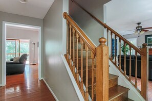 Un escalier avec des balustrades en bois et un ventilateur de plafond dans un intérieur résidentiel.