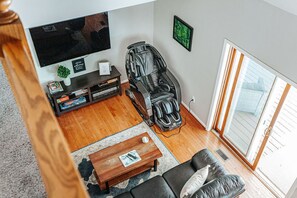Una sala de estar con televisor, sillón de masaje, sofá y una mesa de centro.