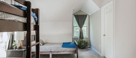 Habitación tipo dormitorio con literas, ventilador de techo, ventana con cortinas y una puerta.