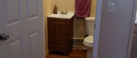 A bathroom with a wooden vanity, a toilet, and a mirror.