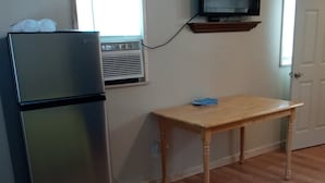A compact kitchen with a stainless steel refrigerator, a wooden table, a window with blinds, and a mounted television. - Big Mountain Cabins with direct access to Windrock ATV Park (OLIVER SPRINGS)