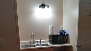 A compact kitchen with a sink, a microwave, and a trash bin. - Big Mountain Cabins with direct access to Windrock ATV Park (OLIVER SPRINGS)