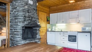 Een keuken met witte kasten, een stenen muur, een houten tafel en een rood kleed.