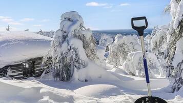 Paesaggio innevato con una baita di legno e una pala in primo piano.