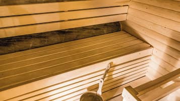 A sauna with wooden benches and a metal bucket.