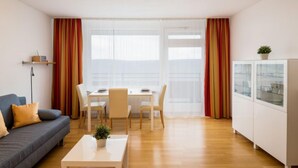 Un salon moderne comprenant un canapé, une table basse, une table à manger avec des chaises et un coin cuisine avec des placards.