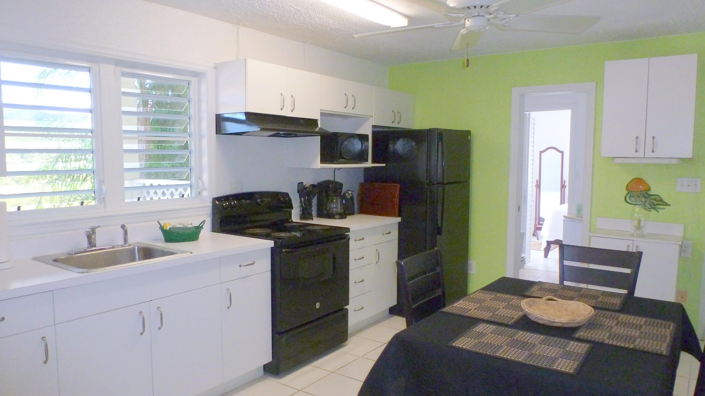 A compact kitchen with white cabinets, a black stove, and a refrigerator.