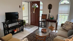 Een woonkamer met een televisie, bank, salontafel en een deur met een welkomstbord.