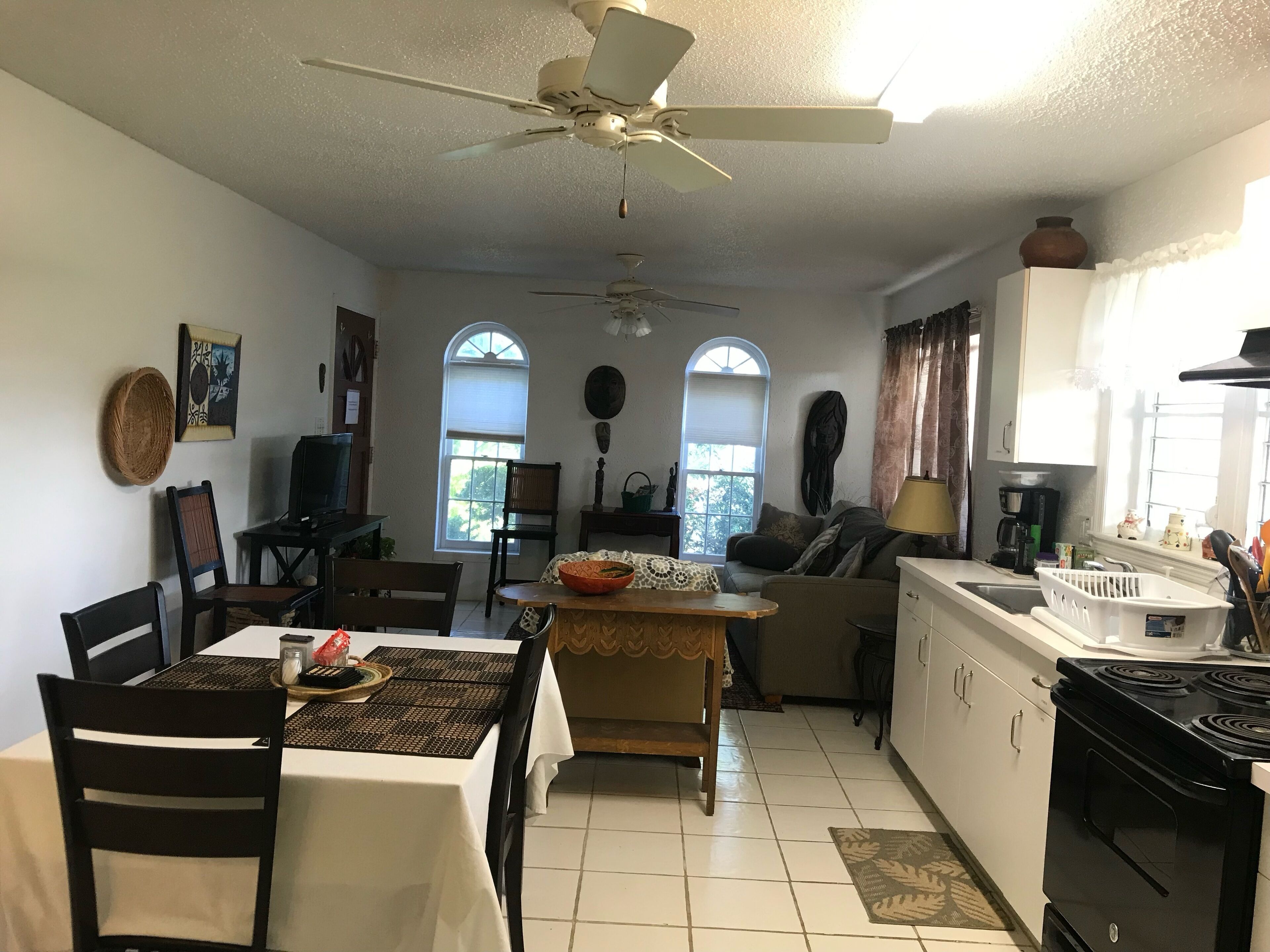 A compact kitchen with a dining area, a ceiling fan, and a window with a view of the outdoors.