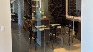 Un interior moderno con un separador de vidrio, un comedor con mesas y sillas, y una cocina visible al otro lado.