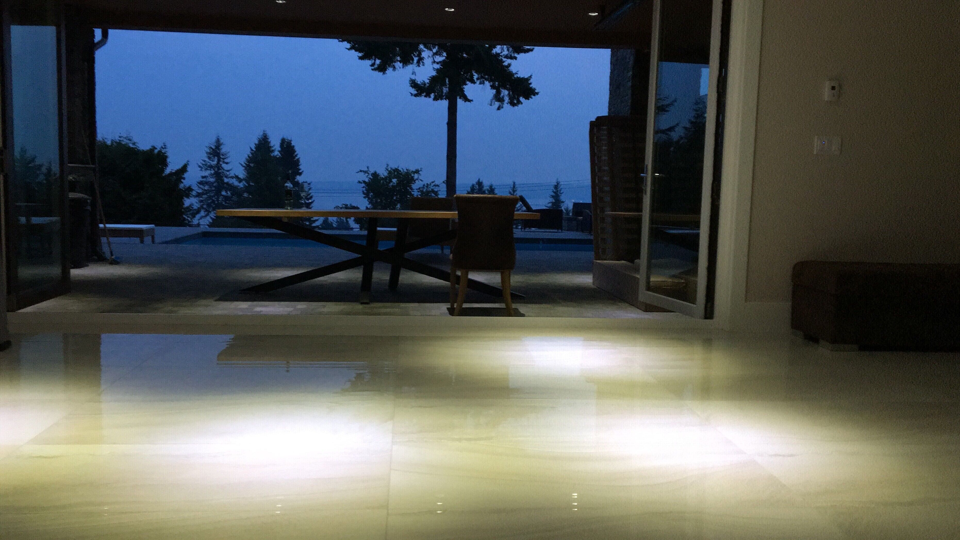 Interior moderno com porta de vidro que dá para o exterior, uma mesa de madeira e um banco.