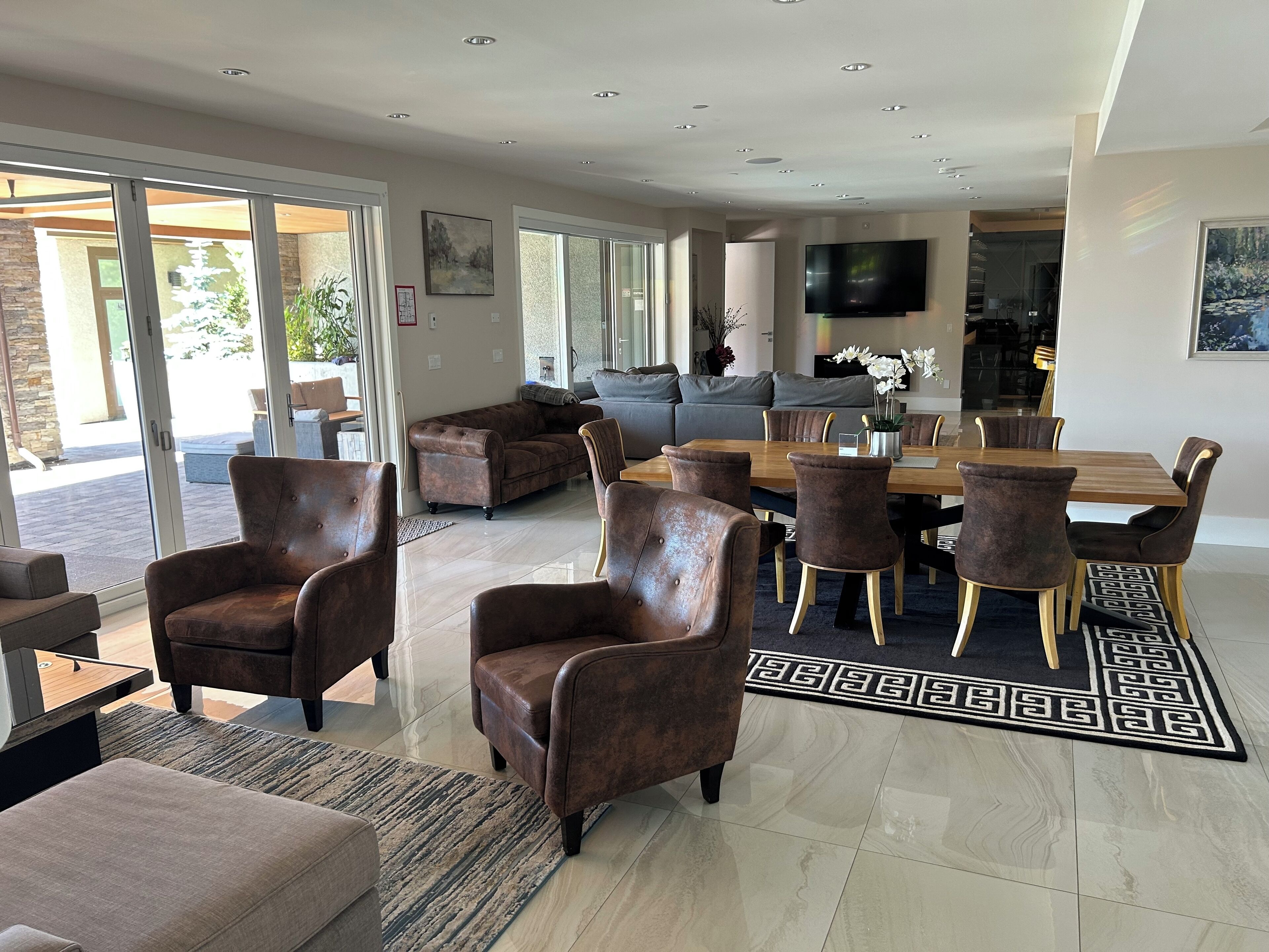 Un salon spacieux avec un grand canapé, une table à manger avec des chaises et un téléviseur fixé au mur.