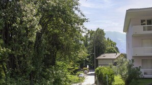 A narrow pathway flanked by dense greenery and a white building with a flat roof. - Simona Fontile 11 by Interhome (Minusio)