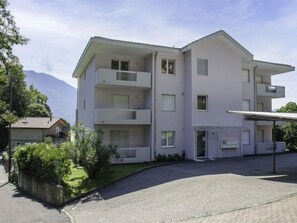 Un edificio a più piani con balconi, un ingresso coperto e una strada privata lastricata.