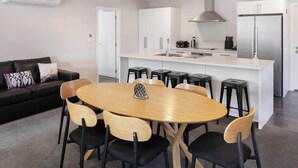 Una cocina moderna con una isla central, armarios blancos y encimera negra.