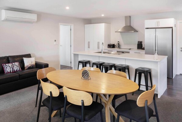 A modern kitchen with a central island, white cabinetry, and a black countertop.