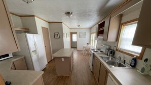 Une cuisine compacte équipée d’un réfrigérateur, d’une cuisinière, d’un évier et d’un petit coin repas.