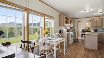 A kitchen with a dining area, large windows, and a view of the outdoors.