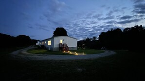 Un bâtiment blanc avec un escalier en bois et une pelouse devant.