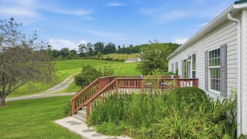 A house with a wooden deck and a gravel pathway leading to a white building.