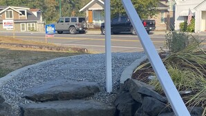 A parking lot with a gravel area, a white pole, and a stone wall. - Gig Harbor Downtown Waterfront Retreat (Gig Harbor)