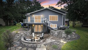 A two-story house with a covered patio, outdoor seating, and a fire pit. - Lake Living on Castle Rock Lake, Close to WI Dells, Family Friendly (Mauston)