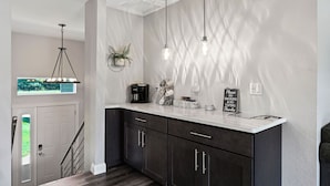 A kitchen with dark cabinets, a white countertop, and pendant lights. There is a coffee maker, a plant, and a sign that says "Please No Smoking & No Vaping Thanks." - Lake Living on Castle Rock Lake, Close to WI Dells, Family Friendly (Mauston)