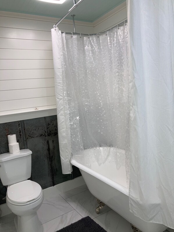 A bathroom with a toilet, bathtub, and shower curtain.