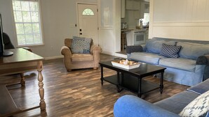 Ein Wohnzimmer mit Holzboden, einem beigen Sessel, einem blauen Sofa und einem Couchtisch.