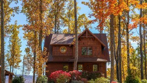 A cabin surrounded by tall trees with autumn foliage. - MountainAire at Eagles Nest -  Views, firepit, gas fire table, Eagles Nest amenities! (Banner Elk)