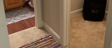 A bathroom with a toilet, a towel rack, a wooden cabinet, and a colorful striped rug.