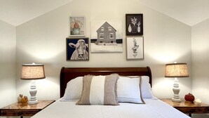 A bedroom with a large bed, two bedside tables with lamps, and wall art including a cow painting and framed pictures. - Private 3 Acre Bungalow (Louisburg)