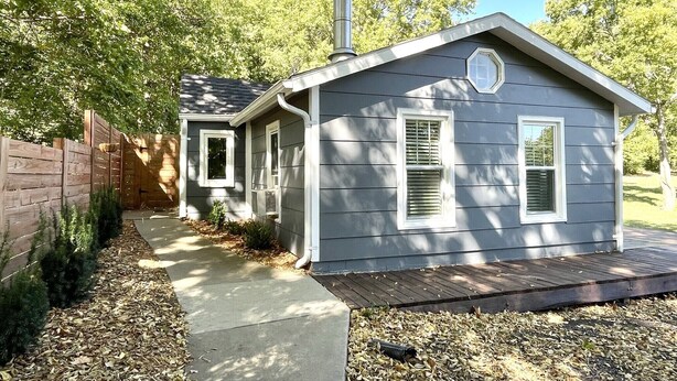 A small, single-story house with a chimney, a covered porch, and a pathway leading to the entrance. - Private 3 Acre Bungalow (Louisburg)