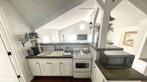A kitchen with white cabinets, a stove, a microwave, and a sink. - Private 3 Acre Bungalow (Louisburg)
