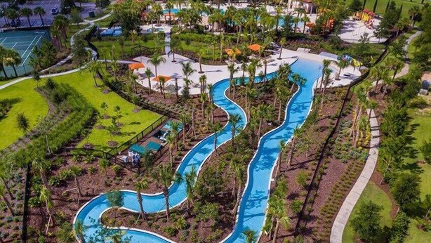 An aerial view of a resort with a winding pool, palm trees, and a tennis court. - Delightful Frozen Potter Lake Home Pool Spa Resort (Davenport)