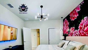 A hotel room with a bed, a TV, a chandelier, and a floral mural on the wall. - Delightful Frozen Potter Lake Home Pool Spa Resort (Davenport)