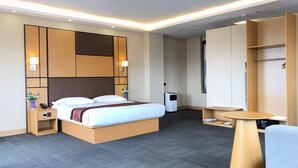 A modern hotel room with a large bed, bedside tables, a desk, and a wardrobe.