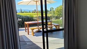 Une chambre dotée d’une grande porte-fenêtre coulissante donnant sur une terrasse extérieure avec une table et des chaises.