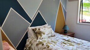 Une chambre à coucher avec un lit, une table de chevet, une lampe et une fenêtre donnant sur un paysage verdoyant.