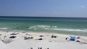 Ein Strand mit weißem Sand, einigen Sonnenschirmen und einem Zelt.