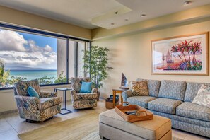 Relax in this serene living room with ocean views, a comfortable seating area, and a beautiful painting.