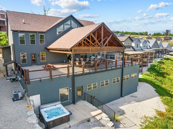 A modern building with a covered outdoor seating area, a hot tub, and a view of neighboring houses.