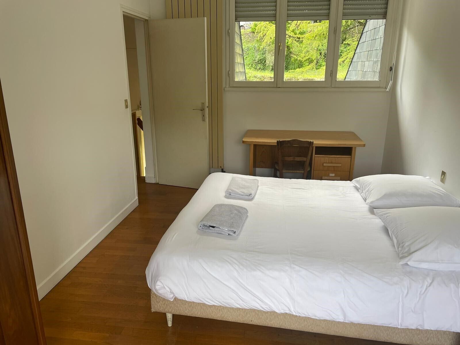 A bedroom with a bed, a desk, and a chair.
