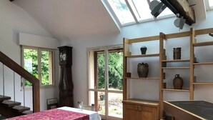 Une pièce comprenant un lit, un bureau en bois, des étagères avec des objets en céramique, une horloge et un escalier.